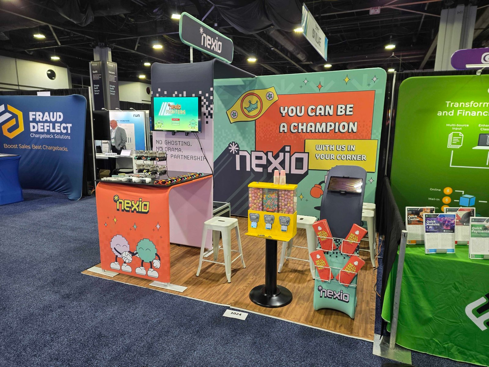 Nexio trade show booth with retro characters, a gumball machine and “With us in your corner” signage